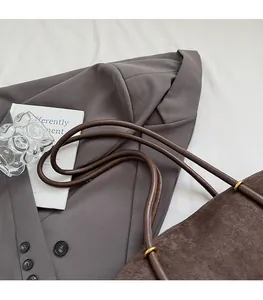 Detail view of dark brown suede shoulder bag straps with elegant gold metal ring connectors