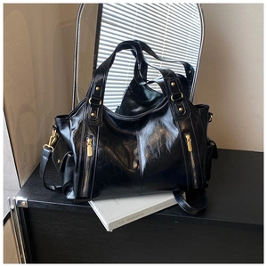 Detail view of black vintage oil wax leather tote with gold zipper accents and side pocket