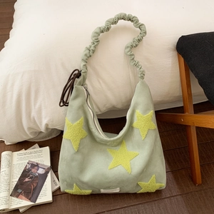 Detail of light green hobo bag with yellow star patches and a ruffled cloud strap