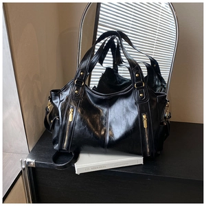 Detail of black glossy tote bag with golden hardware and functional side zippers