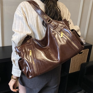 Detail view of a vintage dark brown oil-wax leather tote bag with functional gold zippers