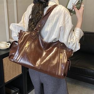 Close-up of vintage brown leather tote bag showing high-texture oil wax finish and dual zippers