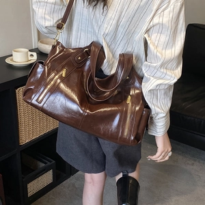 Detail view of deep brown oil-wax leather tote with parallel golden zippers and straps
