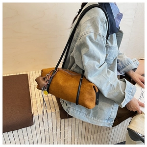 Close-up of vintage brown suede tote bag with decorative pendants on model shoulder