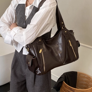 Detail view of deep coffee glossy leather tote bag with gold zippers and side pockets