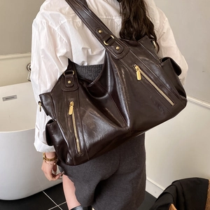 Detail of dark brown vintage tote bag featuring decorative gold vertical zippers