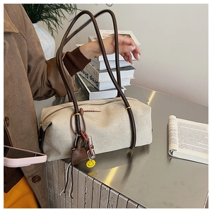 Detail of cream white cylinder shoulder bag with heart pendant and dark brown strap