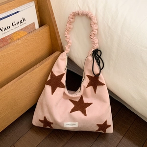 Detail of pink star hobo bag with brown patches and ruffled handle on white bedding