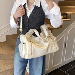 Detail of a large cream Boston tote bag with multiple zippers and retro side pockets