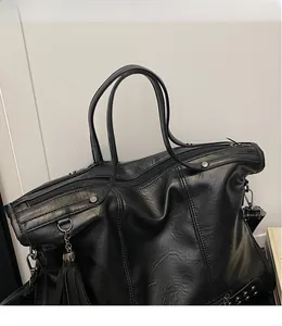 Detailaufnahme der schwarzen Shopper-Tasche mit Nieten, Fransen und Kieselstein-Textur