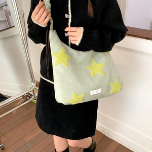 Detail of light green hobo bag featuring 3D yellow star embroidery and brand label
