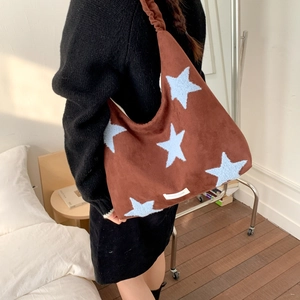 Brown suede hobo bag with blue star patterns shown in a cozy indoor lifestyle setting