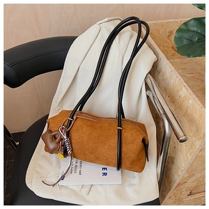 Detailed macro view of the brown suede texture and heart-shaped leather charm on bag