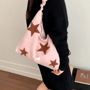 Detail of pink plush shoulder bag featuring brown star patterns and soft wrinkled strap