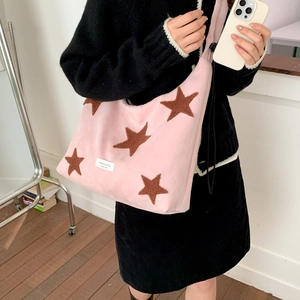 Detailed close-up of pink plush hobo bag featuring brown star patches and logo label