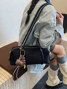 Retro large black cylinder shoulder bag with leather charm and chain shown on model