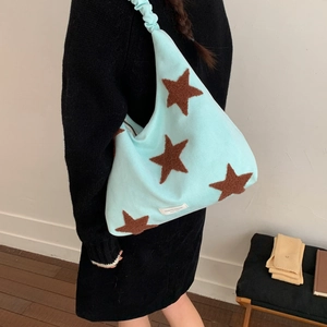 Detail of mint green shoulder bag featuring brown star embroidery and ruched strap design