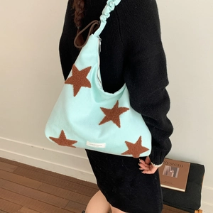 Close-up of mint green canvas bag with brown plush star and pleated strap detail
