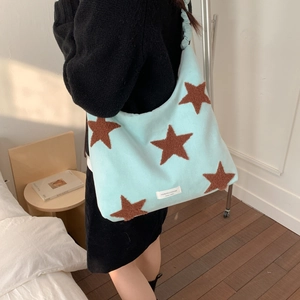 Detail of light blue plush hobo bag showing brown fuzzy star embroidery and soft texture