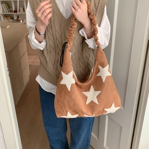 Detail view of brown suede shoulder bag with white stars and ruched cloud strap design