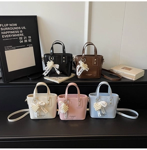 Detalle de bolsos tipo cubo en cinco colores con dijes de corazón de perlas y encaje
