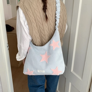 Detail of light blue plush tote bag with pink stars and a stylish scrunchie shoulder strap