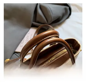 Détail des poignées en cuir marron et de la fermeture éclair dorée sur le sac à main