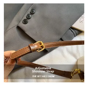 Détail de la bandoulière réglable en cuir marron avec une boucle en métal doré