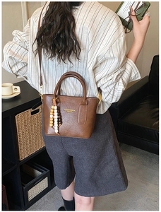 Sac seau en cuir marron avec poignées et pompon décoratif en perles de bois colorées