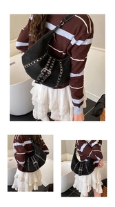 Dettaglio della borsa a mezzaluna nera con borchie argentate e fibbie in stile punk vintage