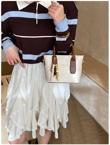 Détail du sac bandoulière crème avec poignée marron et porte-clé à perles en bois colorées