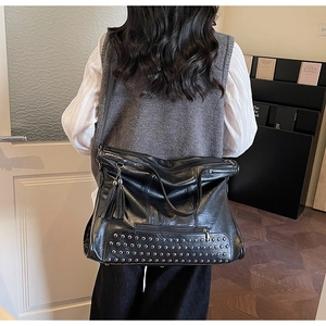 Detail einer schwarzen Leder-Tote-Bag mit silbernen Nieten und schicken langen Quasten