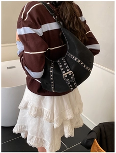 Dettaglio borsa hobo nera con borchie argentate e fibbia con occhielli su modella