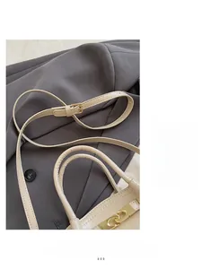 Detail eines verstellbaren Schultergurts mit goldener Schnalle an beiger Tasche