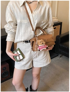 Chic brown patchwork crossbody pillow bag with cute puppy pendant in cozy indoor setting