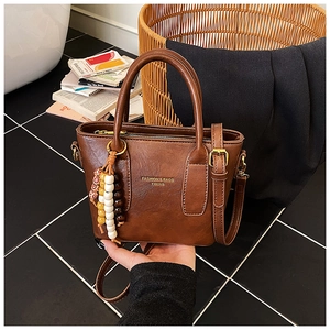 Détail d'un sac à main marron en similicuir avec charme en perles de bois et anse élégante