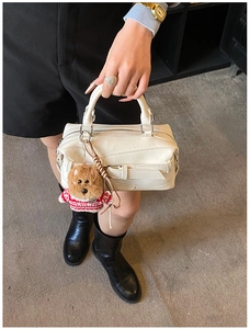 Detail of white litchi pattern handbag with a decorative belt buckle and cute dog charm