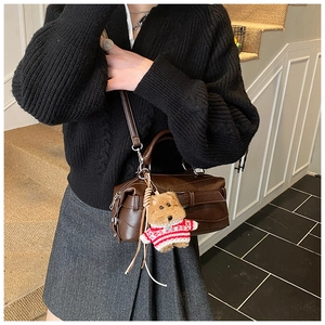 Brown vintage style satchel bag with belt buckle detail and a cute puppy plush charm