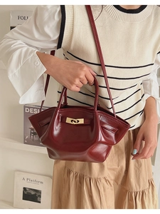 Detailaufnahme weinrote Faltenhandtasche aus Leder mit goldenem Drehverschluss am Outfit