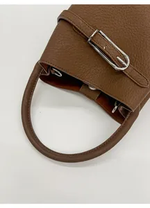 Détail d'un sac à main en cuir grainé marron avec poignée ronde et garniture argentée