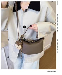 Close-up of brown pebbled leather half-moon crossbody bag with cute teddy bear keychain detail