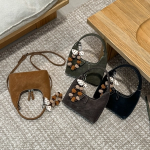 Detail view of suede hobo bags in four colors with decorative bow charms and dual zippers