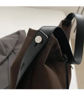 Détail de couture renforcée sur sac en toile marron avec bandoulière en cuir noir