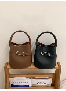 Détail de sacs seaux en cuir grainé noir et marron avec boucles en métal argenté élégantes