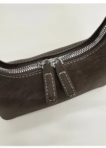 Detail der dunkelbraunen Wildledertasche mit silbernem Doppelreißverschluss und Kontrastnaht