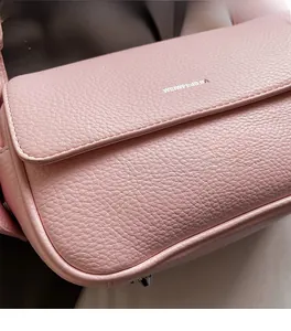 Detailed macro view of pink lychee grain leather texture and white logo on shoulder bag