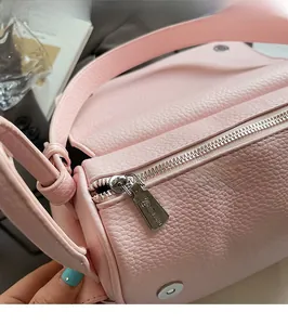 Macro shot of pink lychee leather texture and silver zipper detail on round bag
