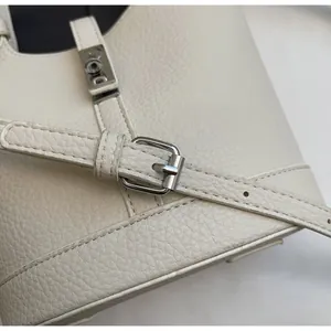 Detalle de la textura de cuero granulado blanco y cierre metálico plateado en el bolso