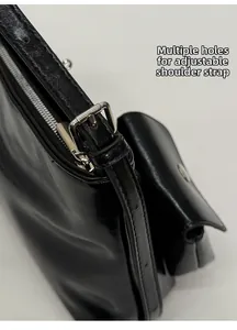 Dettaglio della borsa a spalla nera lucida con fibbia argento e tracolla regolabile forata