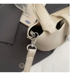 Detalle del cierre de langosta plateado en un bolso saco de cuero beige con textura